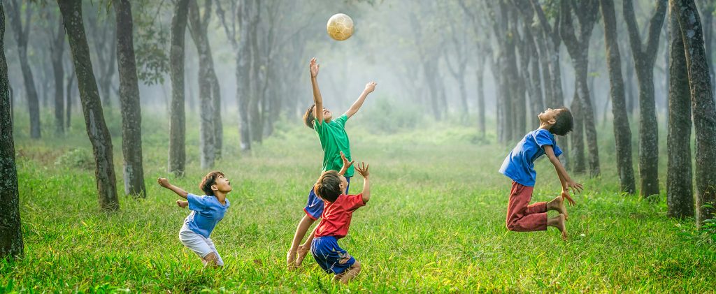 Garçons jouant au ballon avec une éducatrice de jeunes enfants dans le cadre d’un accompagnement avec AEF : Accompagnement Education Famille.